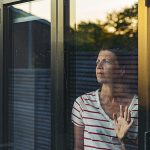 Woman looking through window – negative emotion